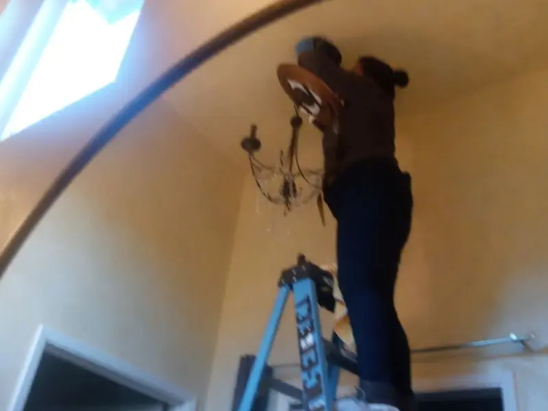 Electrician installing a chandelier in a Yosemite Lakes residence